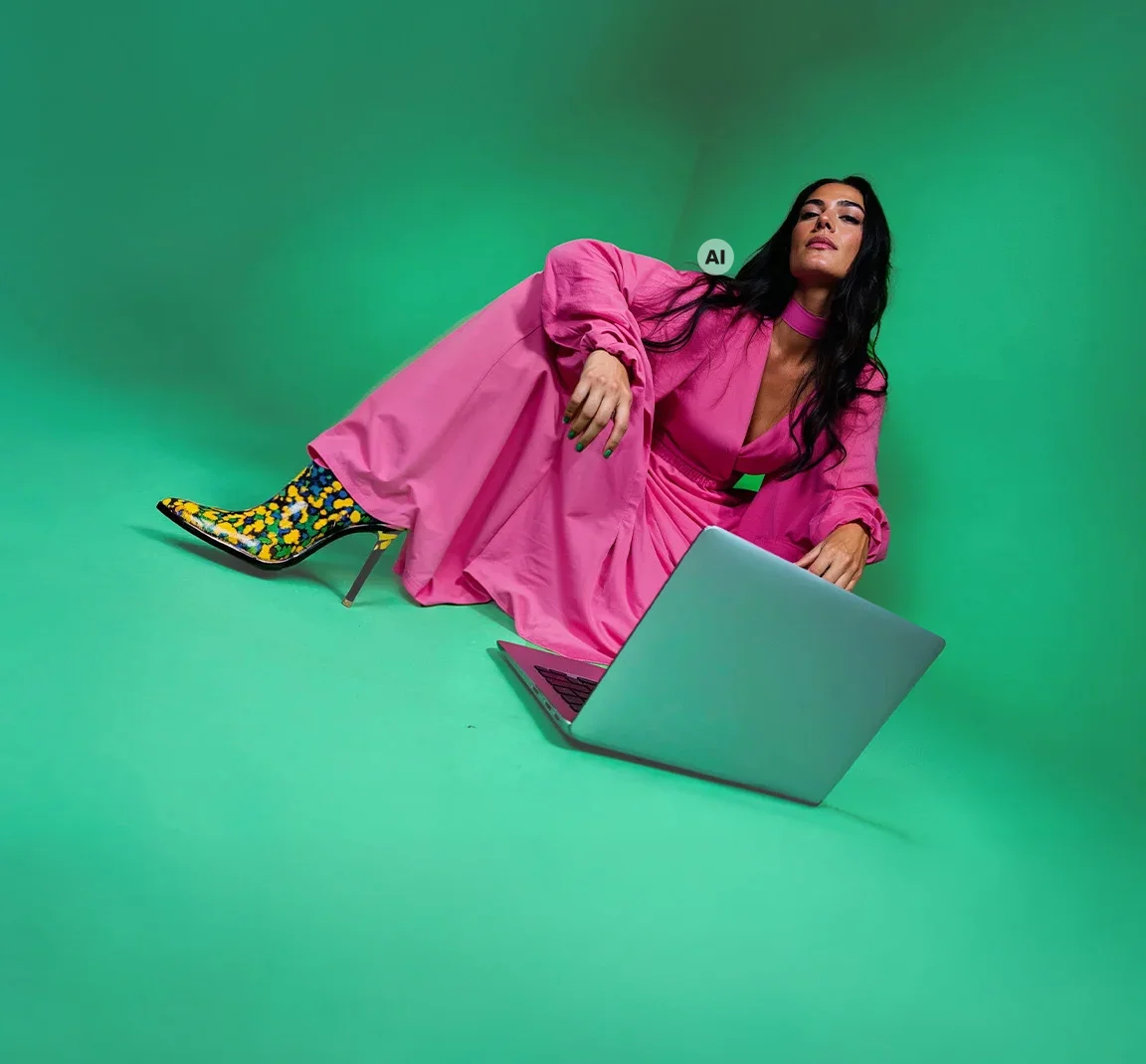 A woman in a pink dress with a laptop